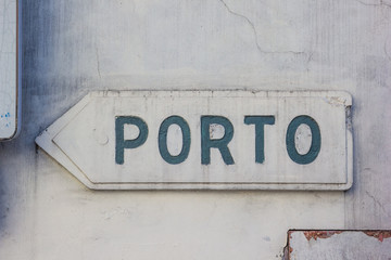 Rustic road sign to Porto an a wall