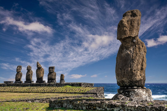 Gro&szlig;e Moai Statue im Vordergrund vor einer Ahu Zeremonialplattform mit vier Moai Skulpturen auf der Osterinsel.