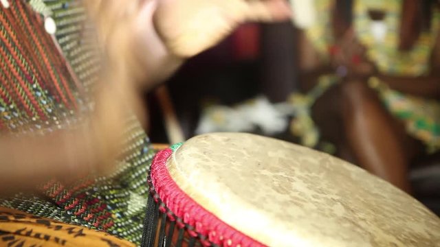 person playing on Jambe Drum no face. Closeup of man's hands drumming out a beat on an African skin-covered djembe hand drum.