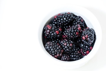 High contrast image of blackberries in a white dish  on a white background.