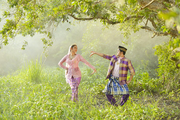 Asian Muslim man and woman wearing traditional dress in dancing action