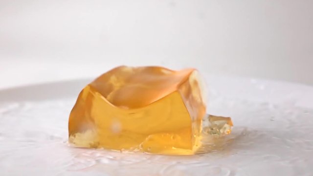 Macro super slow motion video of orange jelly falling in water