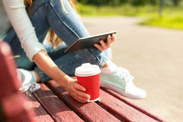Young woman with a coffee to go and tablet pc on a bench