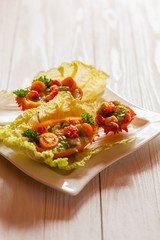 Exotic Shrimp salad served in n half a kiwano and leaves of the Chinese cabbage for summer party on wooden table, selective focus, copy space