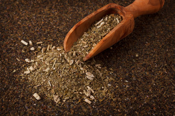 Mate with wooden scoop on wooden background
