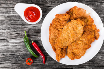 Fried chicken chops on a white dish, top view