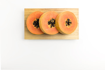 Isolated yellow ripe papaya on wood plate on white background