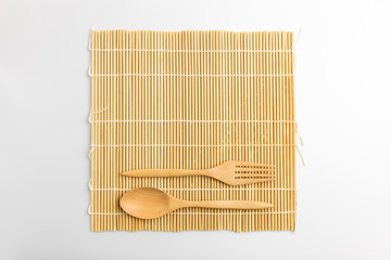 Top view of wooden spoon, fork and mat