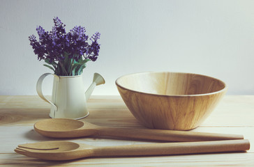 Wooden bowl spoon and fork set with purple artificial flower, still life concept and vintage tone