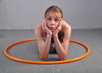 Teenage sportive girl is doing exercises with hula hoop on grey background. Having fun playing game . Sport healthy lifestyle concept. Sporty childhood. Teenager exercising with tool.