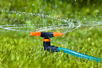 garden sprinkler spraying water over grass