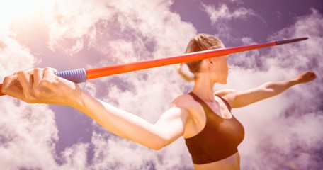 Close up of sportswoman hand holding a javelin  against bright blue sky with clouds