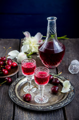 Cherry  liquor in glasses, cherry  and vintage bottle on metal tray.