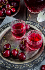 Cherry homemade liquor in a vintage glasses  on metal tray and cherries.