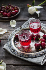 Cherry homemade liquor in a vintage glasses  on metal tray and cherries.