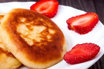 fritters on a plate with strawberries wooden background