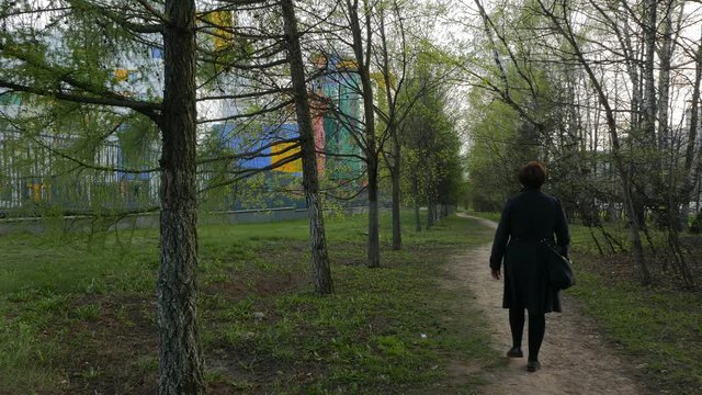 Lonely Woman Walking on a Path Surrounded Trees.