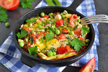 frittata with tomatoes, peppers, green peas and feta cheese in a