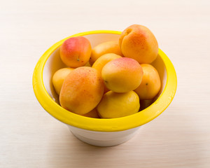 The simple food composition with apricots in the bowl on the unique backing closeup