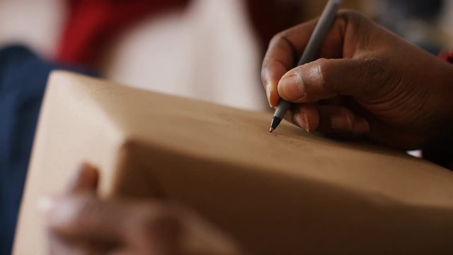 4K Hand writing an address on a parcel, in slow motion
