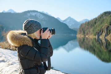 a woman photographer is taking picture of the Alpsee landscape, Germany