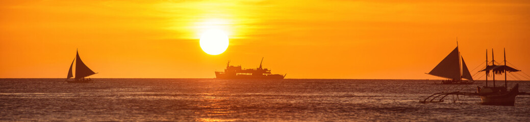 Fototapeta premium A wide view of the sea and a boat at a sunset in Boracay island