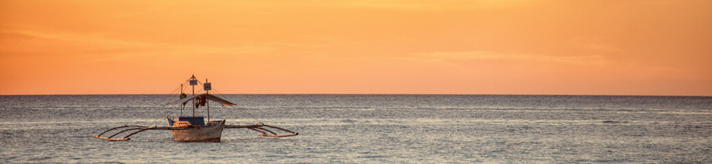 A wide view of the sea and a boat at a sunset in Boracay island