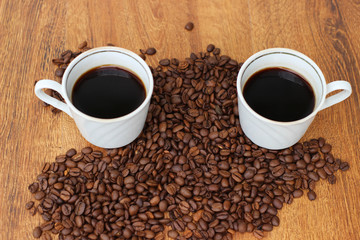 Two White Coffee mug with coffee beans on a wooden background closeup