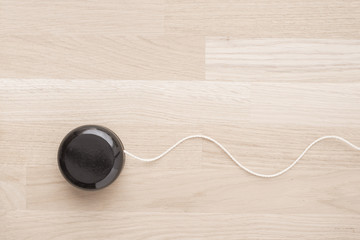 Black wooden yoyo on table. Close up of vintage toy. Concept of nostalgia, childhood and old-fashioned entertainment.