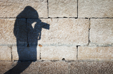 Obraz na płótnie Canvas Shadow of a photographer photographing on sunny stone street.