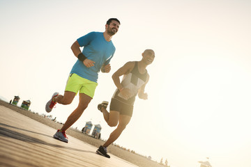 Fitness people running at the beach into the sunset.