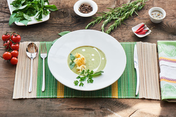 Soup with zucchini in a white plate on a wooden table