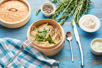 Homemade dumplings in a wooden pot and rustic cream on the table