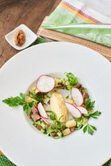 Top view of the blank for okroshka with beef in white plate on wooden table