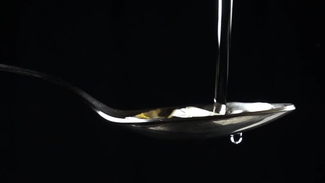 Super slow motion close up shot of sunflower oil being poured in spoon