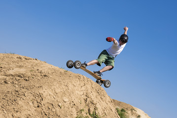 Skateboarder doing a jumping trick at skateboard park with mountainboard