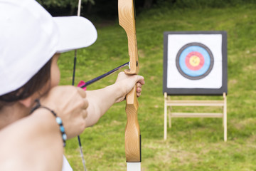 An young girl is shooting with a recurve bow on a target during an archery competition