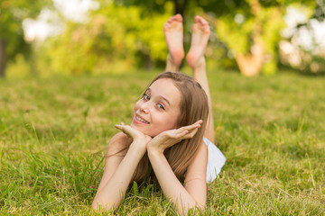 Portrait of a beautiful young girl lying on the grass outdoors in summer