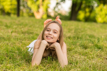 Portrait of a beautiful young girl lying on the grass outdoors in summer