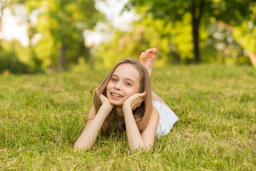 Portrait of a beautiful young girl lying on the grass outdoors in summer