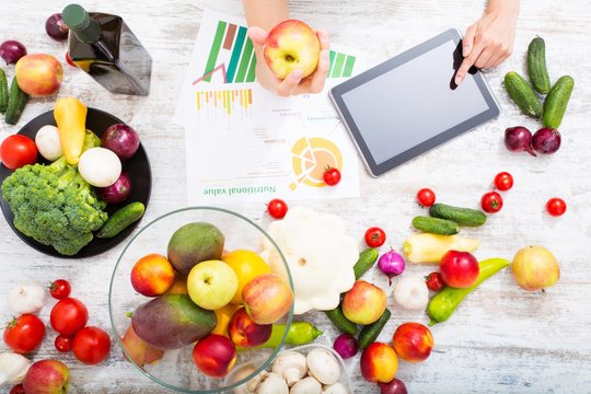 Close-up of a young adult woman informing herself with a tablet PC about nutritional values of fruits and vegetables..