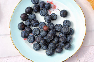 Freshly picked blueberries in wooden bowl. Juicy and fresh blueberries with green leaves on rustic table. Bilberry on wooden Background. Blueberry antioxidant. Concept for healthy eating and nutrition