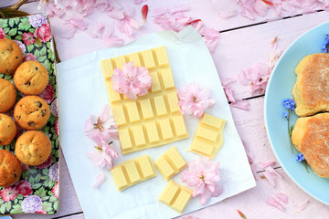 A bar of white chocolate with Japanese cherry blossom flowers and fresh muffins