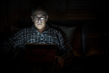 Man reading tablet at night