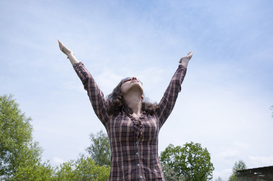 Girl in shirt holding out his hands to the sky