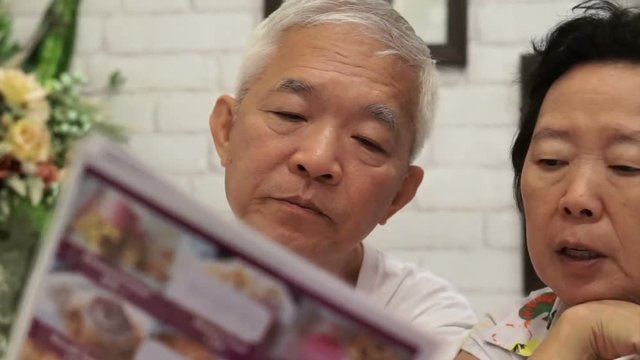Asian senior couple looking at menus in a restaurant together