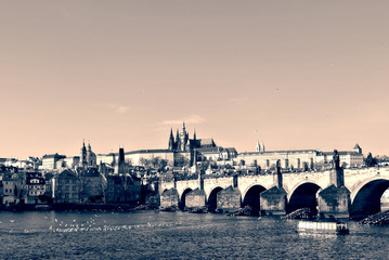 Charles' bridge and Hradcany castle in Prague, in black and white, on a sunny day. Monochrome cityscape filtered in retro, vintage style with soft focus and red filter. - 113583126