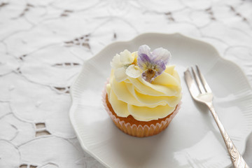 yellow cupcakes with  sugared edible flowers on vintage plate
