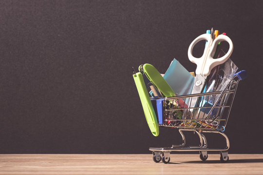 Shopping cart with school supplies over chalkboard background