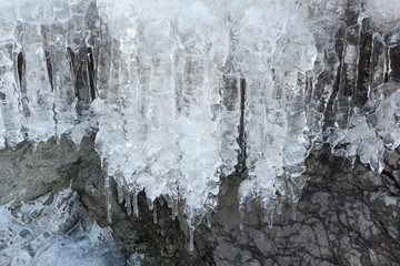 Fototapeta na wymiar Icicles on stones at the thawing river in the spring
